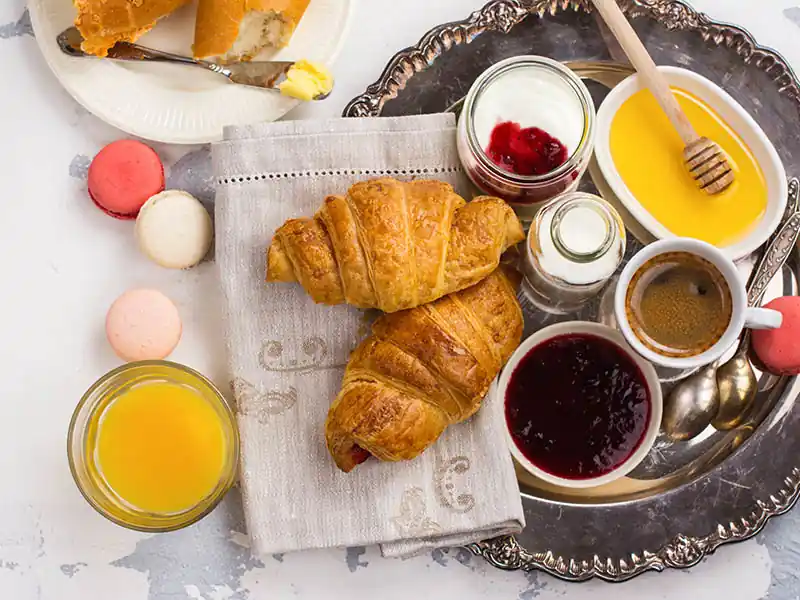 Croissants, orange juice, coffee, honey and jam.